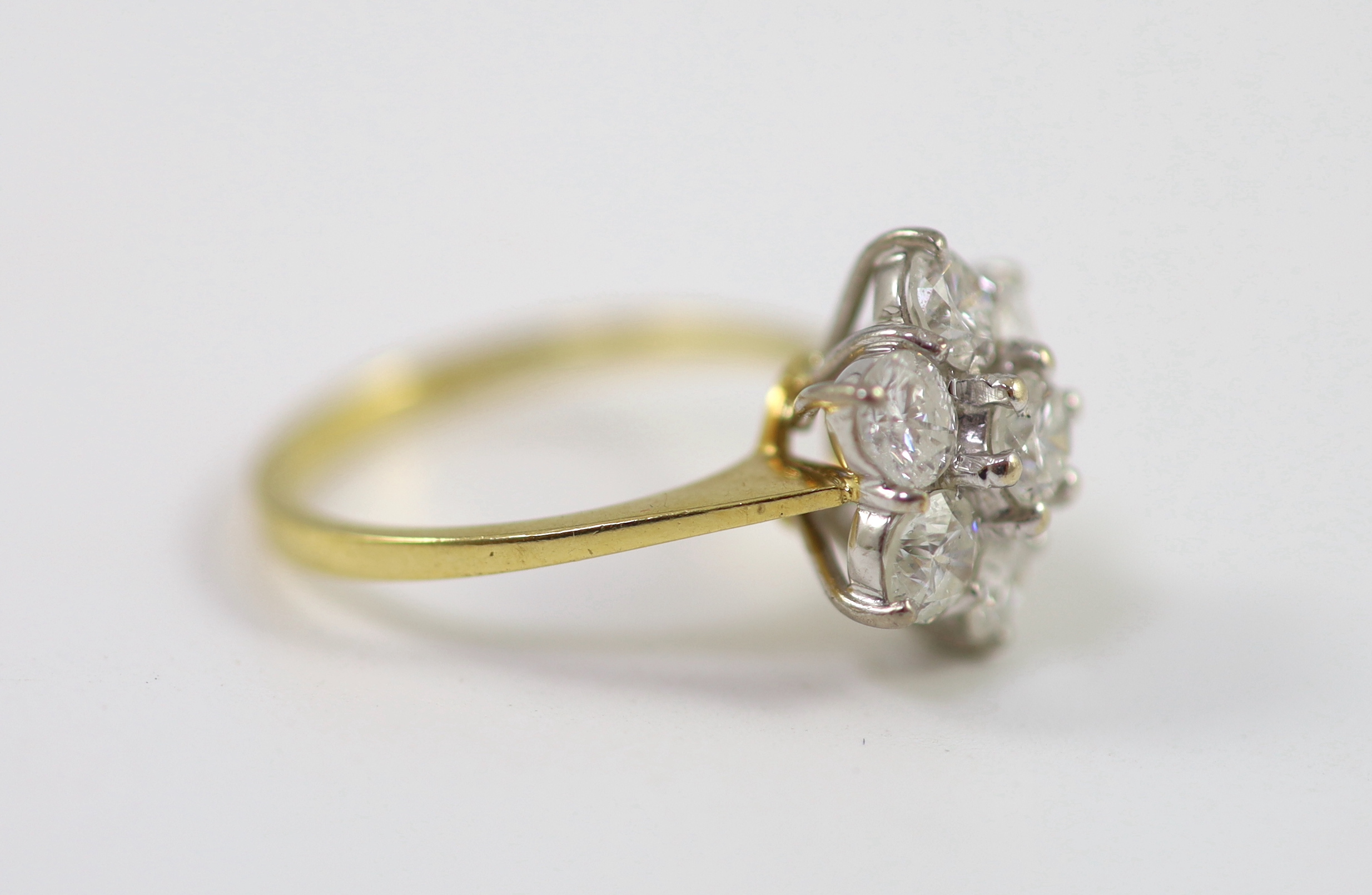 A modern 18ct gold and seven stone diamond set flower head cluster ring